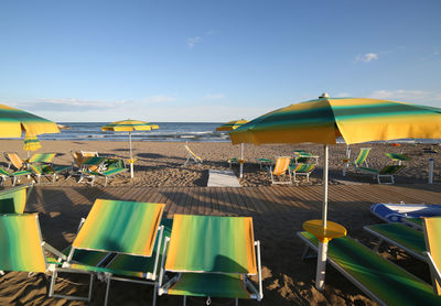 Chairs and parasols on beach against sky