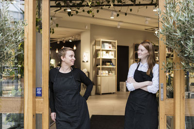 Smiling female owners standing at doorway of store