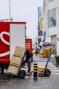 Side view of man loading boxes on luggage cart on street