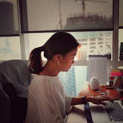 Young woman using mobile phone while sitting on table