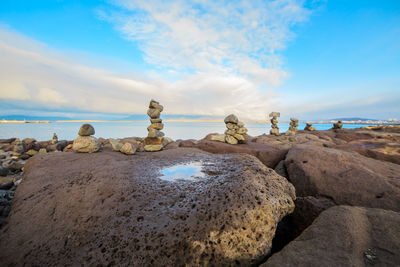 Rocks on beach against cloudy sky
