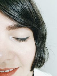 Close-up portrait of young woman wearing make-up against white background