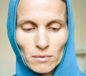 Close-up of thoughtful mature woman in hooded shirt