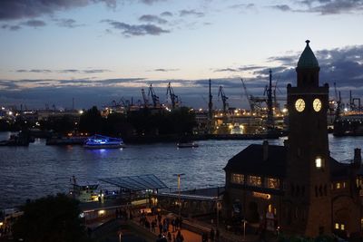 View of city at waterfront against cloudy sky