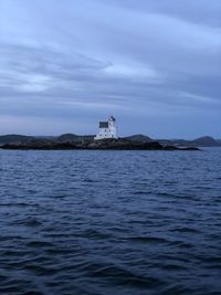 Lighthouse by sea against sky