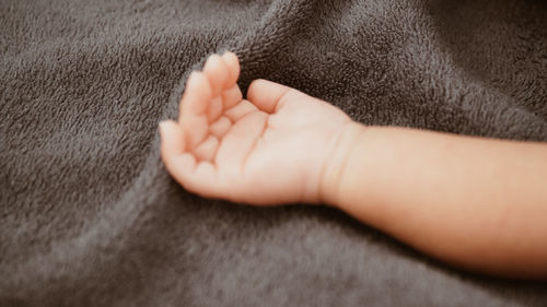 Close-up of human hand on bed