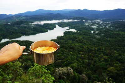 Midsection of person holding bread against mountains