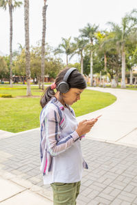 Side view of young woman standing against trees