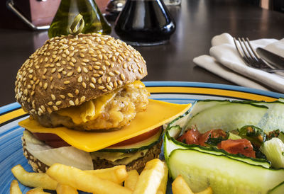 Close-up of cheeseburger with french fries in plate on table