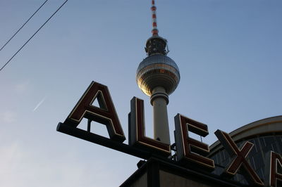 Low angle view of text and fernsehturm against sky