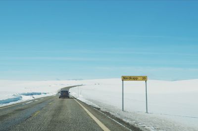 Car on country road by information sign on snow covered field