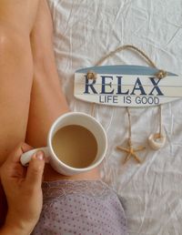 Low section of woman holding coffee cup on table