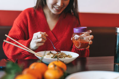 Beautiful young asian woman in red clothes eating noodles with chopsticks in chinese  restaurant