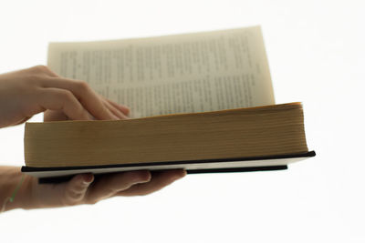 Close-up of hand holding book against white background