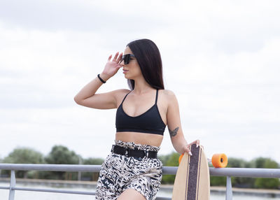 Full length of woman holding railing against sky