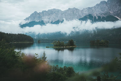 Scenic view of lake and mountains against cloudy sky