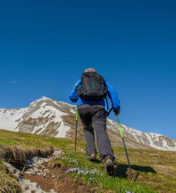 Rear view of man standing on mountain against clear blue sky