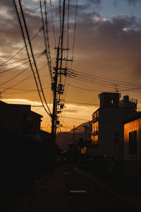 Electricity pylon in city against sky during sunset