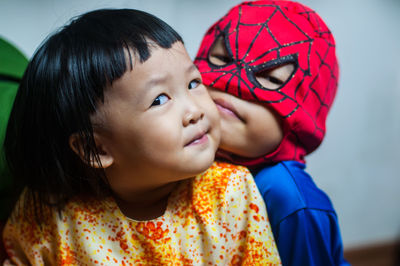 Close-up of boy in superman costume with sister at home