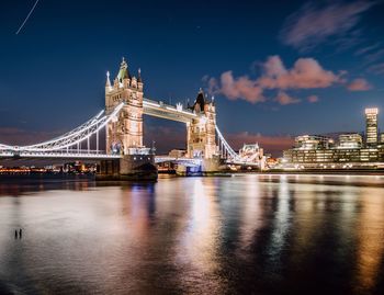 Illuminated tower bridge over thames river against sky at night