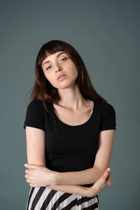 Portrait of beautiful young woman against gray background