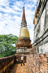 Low angle view of buddha statue against cloudy sky