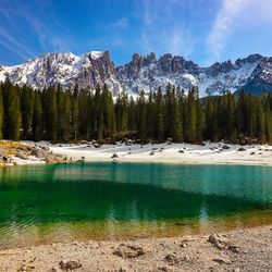 Scenic view of lake by snowcapped mountains against sky