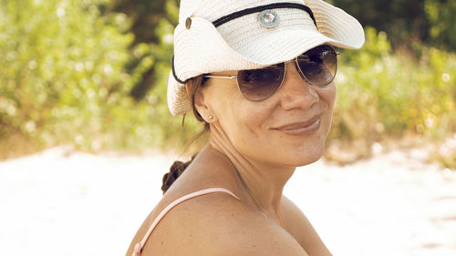 Portrait of smiling woman wearing hat at beach