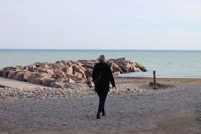 Rear view of woman on beach against clear sky