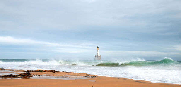 Lighthouse amidst sea against sky