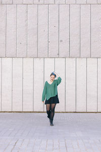 Full length of woman standing against wall