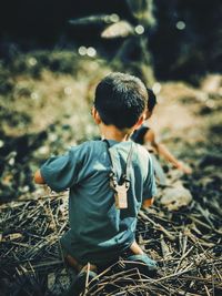 Rear view of boy sitting on field