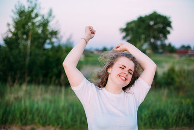 Woman with arms raised standing on field