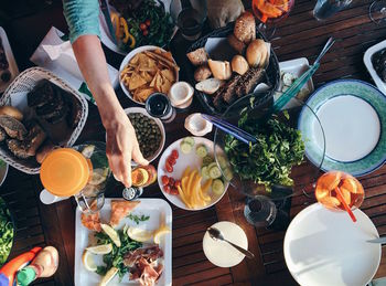 Cropped hand of woman having food at table in home