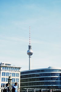 Communications tower in city against sky