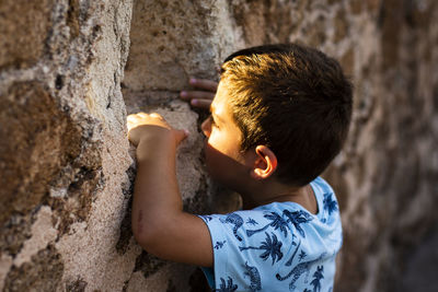 Close-up of boy looking through hole in wall