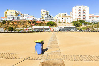 Garbage cans on empty beach in front of city