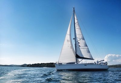 Sailboat sailing on sea against clear sky