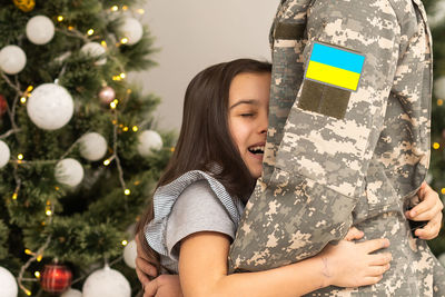 Portrait of woman holding christmas tree at home