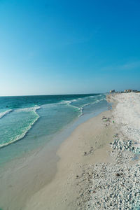 Scenic view of beach against clear blue sky