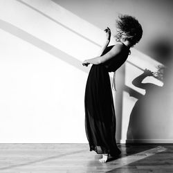 Woman holding umbrella while standing against wall