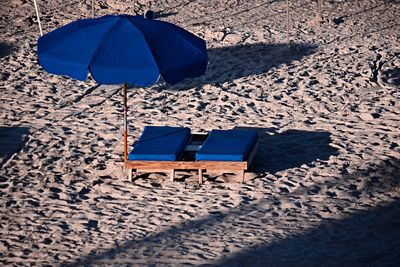 High angle view of blue lounge chairs and parasol at beach