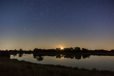 Scenic view of lake against sky at night