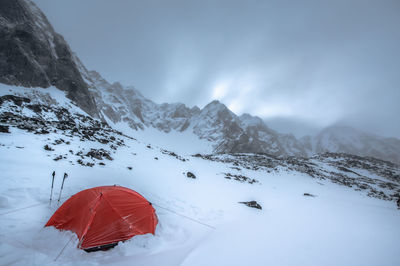 Scenic view of orange tent and snow covered mountains against sky