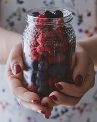 Midsection of woman holding berries in jar