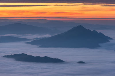 Scenic view of silhouette mountains against orange sky