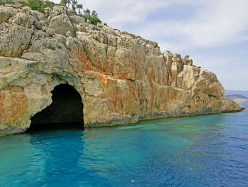 Rock formation by sea against sky