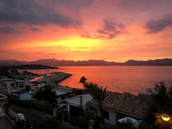 High angle view of townscape by sea against orange sky