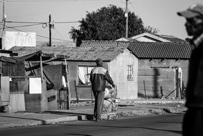 Rear view of man walking on street against buildings