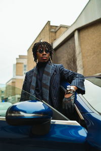 Man wearing sunglasses standing against car